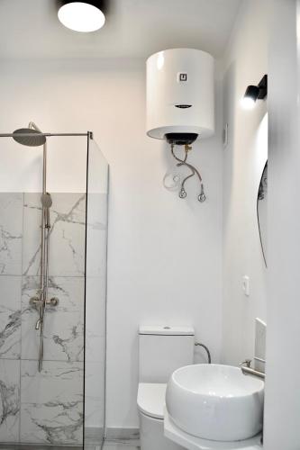 a white bathroom with a toilet and a sink at Tzatziki Studios in Kavala