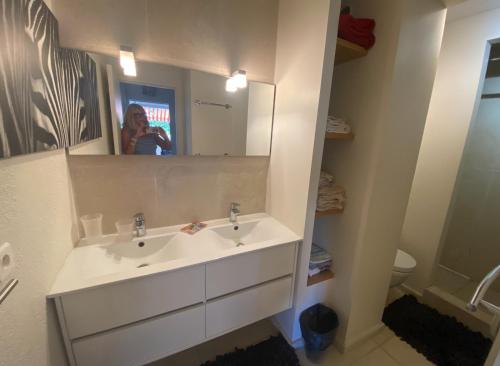 une femme prenant une photo d'une salle de bains avec lavabo dans l'établissement Appartement 4 p avec grande terrasse, piscine, parking dans Saint Tropez centre, à Saint-Tropez