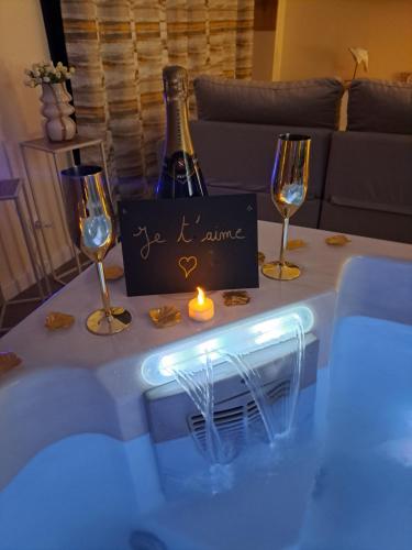 a table with a bottle of wine and two glasses at Les suites d'Élise - Gîte Agathe in Grumesnil