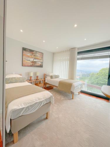 a bedroom with two beds and a large window at Villa Isobel in Vila Verde