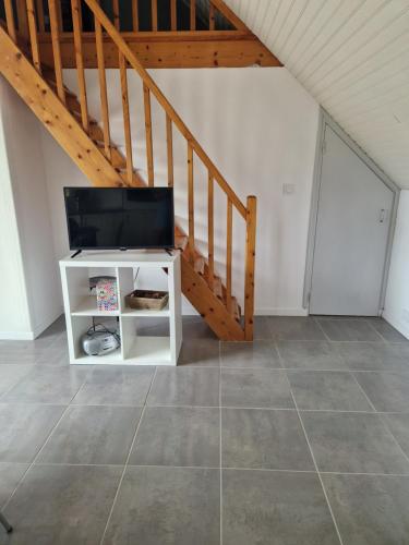 un salon avec une télévision et un escalier dans l'établissement Maison 10 min de la plage, à Saint-Gildas-de-Rhuys