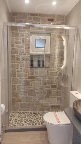 a bathroom with a toilet and a stone wall at Gea luxury apartment Myrina 2 in Myrina