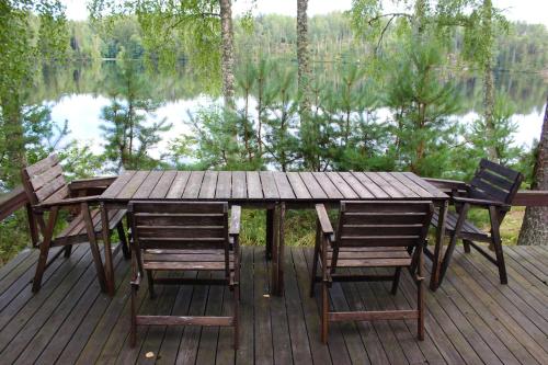 a wooden table and chairs on a deck with a lake at Cozy Cabin by the Lake in Gennarby