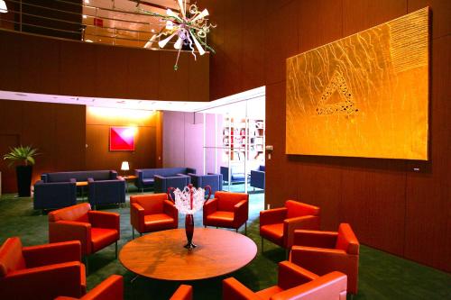 a waiting room with red chairs and a table and a painting at Oriental Hotel Hiroshima in Hiroshima