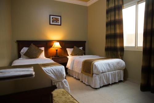 a hotel room with two beds and a window at ضيافة بيت المسرة للشقق المخدومة in Al Khobar