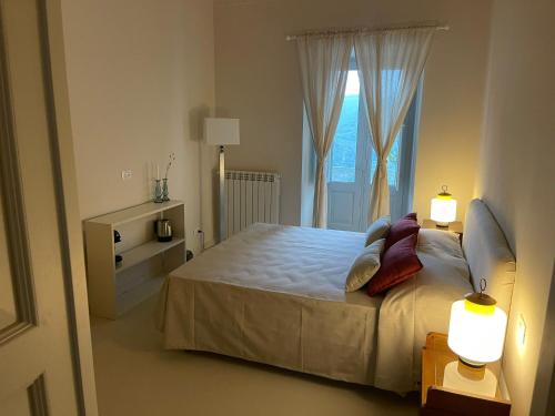 a bedroom with a bed with two lamps and a window at La Dimora di Pindaro in Colledimacine
