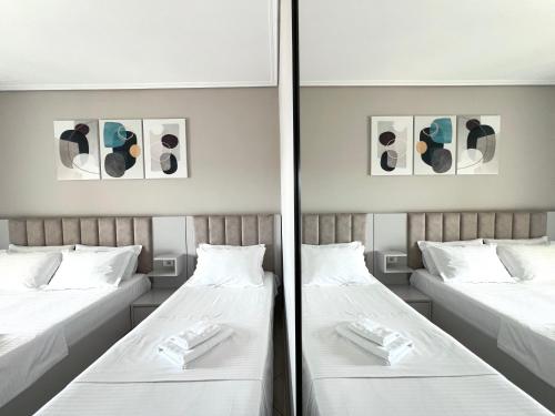 two twin beds in a room with two mirrors at Prestige Home KSAMIL in Ksamil