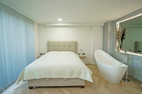 a bedroom with a white bed and a bath tub at MARVEL apartamentai in Kaunas