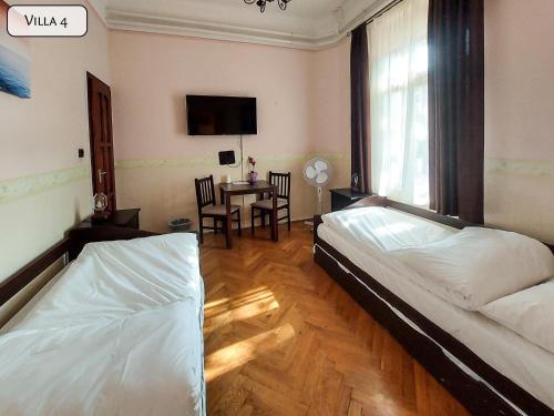 a bedroom with two beds and a table with a tv at Gosztonyi Villa in Siófok