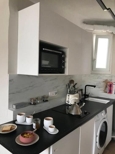 une cuisine avec un comptoir noir avec un micro-ondes dans l'établissement Charmant appartement Batignolles, à Paris