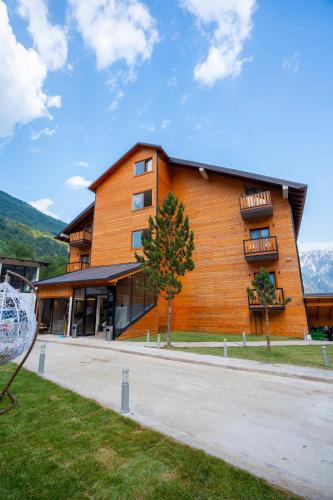 a large wooden building with a balcony on the side at Hotel Jezerca Theth in Theth