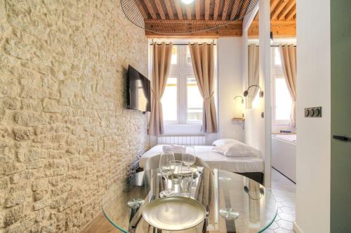Cette chambre comprend un lit et une table en verre. dans l'établissement Studio de charme avec balnéo, coeur de Presqu'île, à Lyon