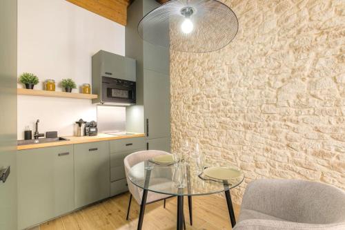 une cuisine avec une table en verre et deux chaises dans l'établissement Studio de charme avec balnéo, coeur de Presqu'île, à Lyon