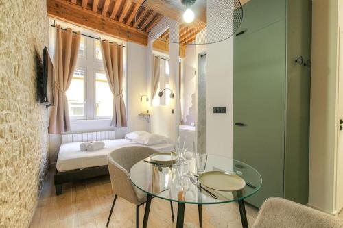Cette chambre comprend une table en verre et un lit. dans l'établissement Studio de charme avec balnéo, coeur de Presqu'île, à Lyon