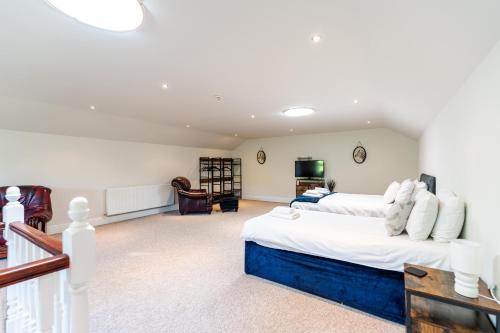 a large room with two beds and a television at The House @ Sitwell Arms Hotel in Renishaw