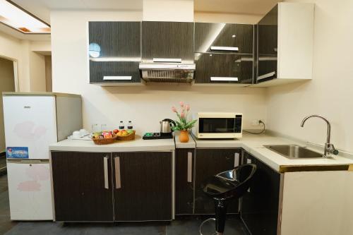 a kitchen with black and white cabinets and a sink at Royal Residence Dhaka in Dhaka
