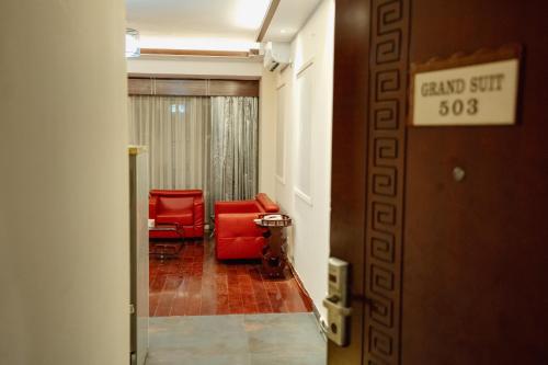 a hallway with two red chairs and a waiting room at Royal Residence Dhaka in Dhaka