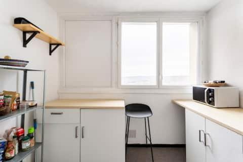 une cuisine avec des armoires blanches et un tabouret et deux fenêtres dans l'établissement Logement avec vue panoramique proche d'Orly, à Longjumeau