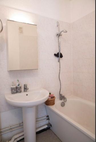 une salle de bain blanche avec un lavabo et une baignoire dans l'établissement Logement avec vue panoramique proche d'Orly, à Longjumeau