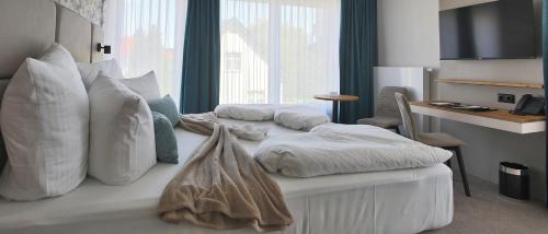 a white bed with pillows on it in a room at Sandbank Hotel & Appartements Lubmin in Lubmin