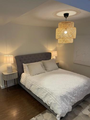 1 dormitorio con cama blanca y lámpara de araña en Cozy and modern Pemberton Heights Suite, en North Vancouver