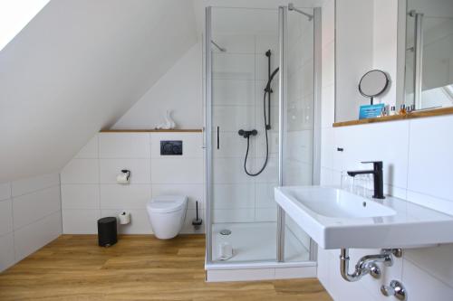 a white bathroom with a shower and a sink at Sandbank Hotel & Appartements Lubmin in Lubmin