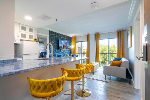 a kitchen with yellow bar stools and a living room at Cozy apt 2 bedrooms 1 mile Universal Studios in Orlando