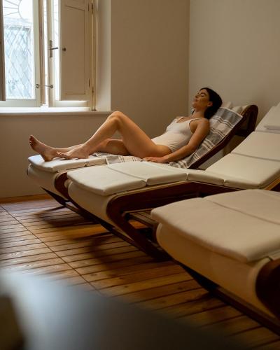 a woman laying on a row of beds in a room at Bellavista Lakefront in Riva del Garda