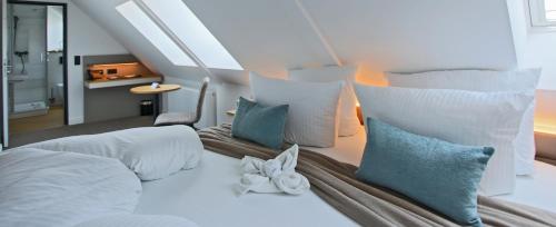 a bedroom with a large white bed with blue pillows at Sandbank Hotel & Appartements Lubmin in Lubmin