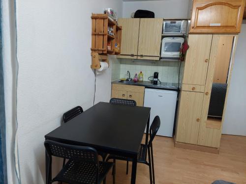 une petite cuisine avec une table et des chaises noires dans l'établissement Studio Pyrénées 2000 Font Romeu, à Bolquère-Pyrénées 2000