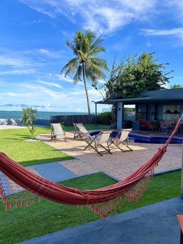 a hammock in front of a resort with a beach at Casa Ilha| beira mar, piscina aquecida, 4 suítes in Marechal Deodoro