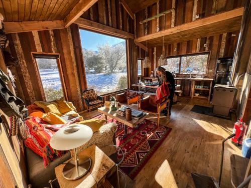 a woman is sitting in a living room in a cabin at Casa La Lenga Patagonia in Villa Cerro Castillo
