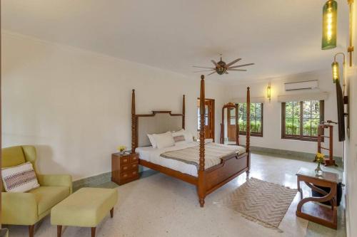 a bedroom with a four poster bed and a chair at Casa Dolce Vita 4 bed villa with a pvt pool in North Goa in Bardez