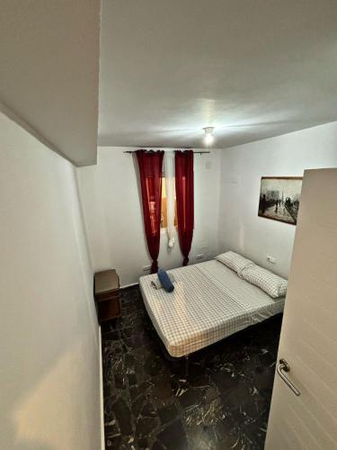 a small room with a bed and red curtains at Casa Amparo in Jávea