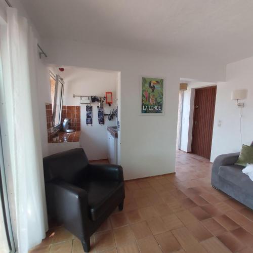 - un salon avec une chaise noire et un canapé dans l'établissement La Londe -Studio T1 - Sur la colline, à La Londe-les-Maures