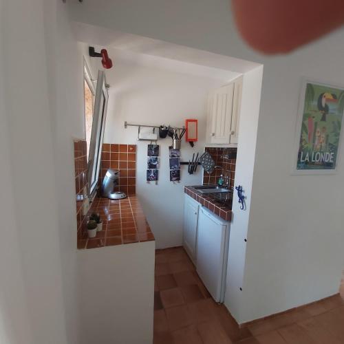 - une petite cuisine avec des placards blancs et du carrelage brun dans l'établissement La Londe -Studio T1 - Sur la colline, à La Londe-les-Maures