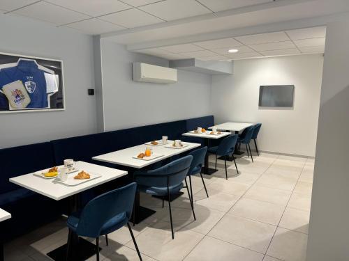 Kyriad Saumur Hyper Centre Hôtel, Appartements, Séminaires et SPA soins Sothys Paris في سوموور: غرفة طعام مع طاولات بيضاء وكراسي زرقاء