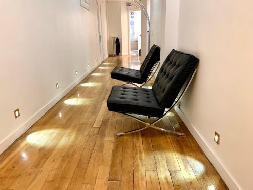 deux chaises noires dans une pièce vide avec du parquet dans l'établissement New! Apartment Luxury Passy-Kennedy in front of Eiffel Tower, à Paris