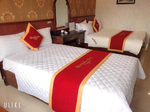 a hotel room with two beds and a mirror at Khách Sạn Nam Sơn in Ðông Khê