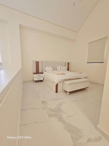 a white room with a bed and a table at B36 Loft Apartment Samarah Resort in Sowayma
