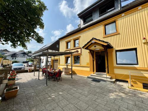 a table and chairs in front of a yellow building at Hotel Moji 3 Landhaus Köln in Lindlar