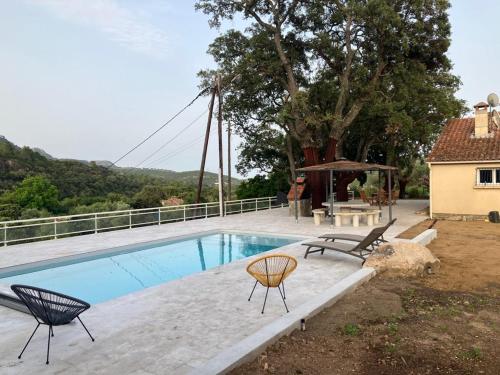 - une piscine avec 2 chaises et une table à côté d'une maison dans l'établissement A SUARELLA - Villa climatisée - 4 chambres - piscine chauffée, à Sainte-Lucie de Porto-Vecchio