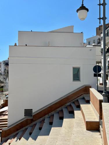 a white building with benches and a street light at Casa La Salsa in Pisticci