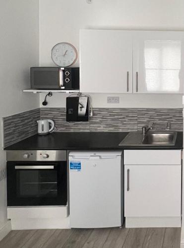 Il comprend une cuisine équipée d'une cuisinière, d'un évier et d'un réveil. dans l'établissement Cosy Self contained Studio flat, à Londres