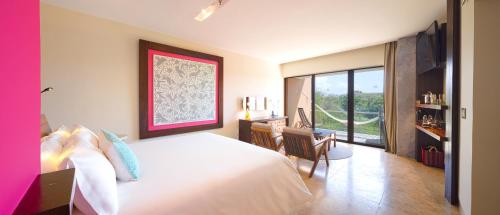 a bedroom with a bed and a desk and a window at Hotel Xcaret Mexico All Parks All Fun Inclusive in Playa del Carmen