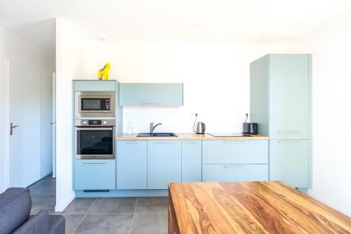 une cuisine avec des placards bleus et une table en bois dans l'établissement Maisonnette de charme au calme, à Pontenx-les-Forges