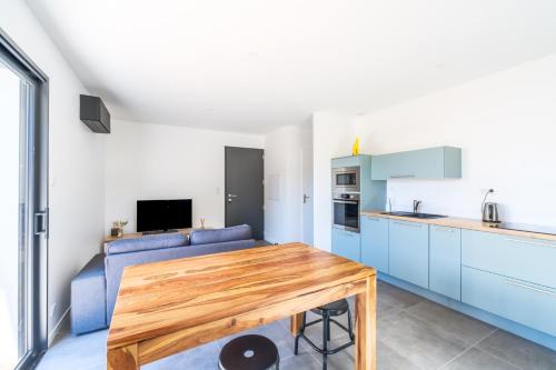 une cuisine avec une table en bois et un canapé bleu dans l'établissement Maisonnette de charme au calme, à Pontenx-les-Forges