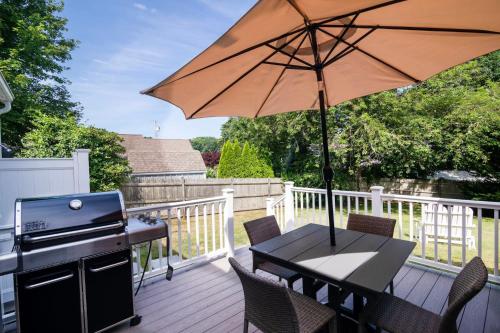 a patio with a table with an umbrella and a grill at Located on Rail Trail By Beach & Downtown in Chatham