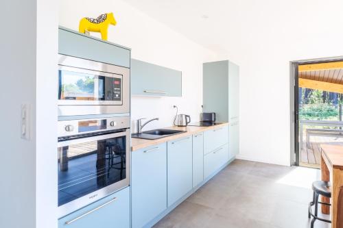 une cuisine avec des armoires blanches et des appareils bleus dans l'établissement Maisonnette de charme au calme, à Pontenx-les-Forges