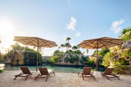 a group of chairs and umbrellas on a beach at Hotel Xcaret Mexico All Parks All Fun Inclusive in Playa del Carmen